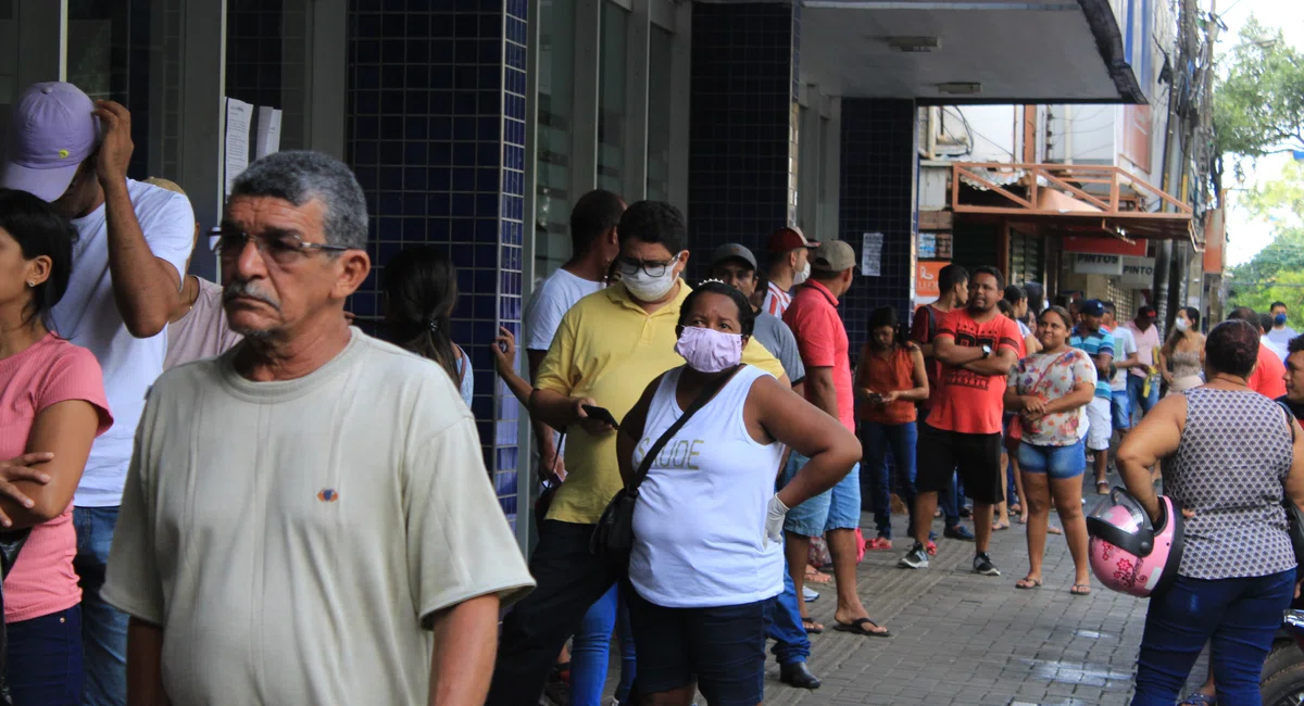 Aglomeração de pessoas em frente a bancos