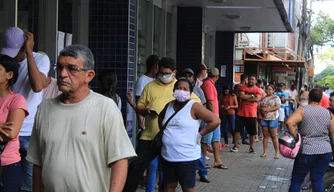 Aglomeração de pessoas em frente a bancos