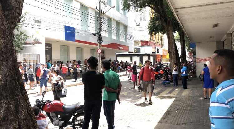 Aglomeração de pessoas em frente a bancos