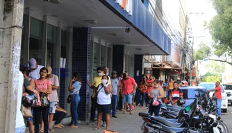 Aglomeração de pessoas em frente a bancos