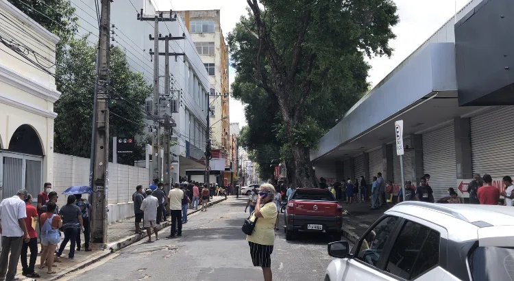 Aglomeração de pessoas em frente a bancos