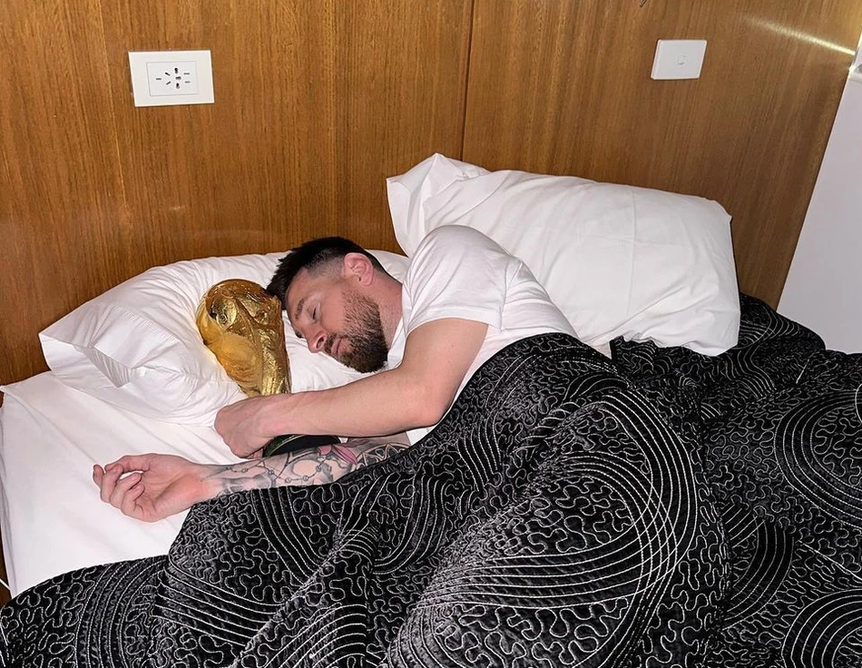 Messi dorme com taça da Copa do Mundo.