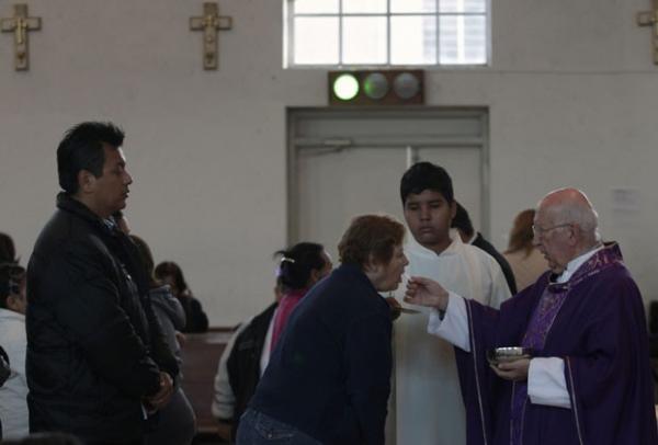 Padre católico distribui a Sagrada Comunhão para a congregação como uma luz verde está acesa dentro da igreja de Santa Teresa de Ávila em Monterrey(Imagem:Reprodução)