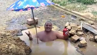 Morador protesta tomando banho dentro de buraco